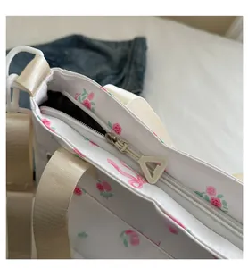 Close-up of the smooth silver metal zipper on a white canvas tote with red rose prints