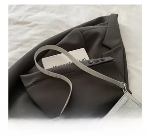 Detail of grey woven shoulder bag with elegant silver metallic bow charm and sleek strap