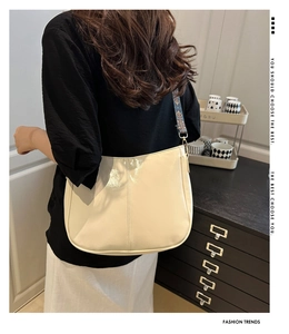 Detail of a creamy white hobo bag with a stylish embroidered colorful wide shoulder strap
