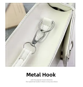 Detail of silver metal hook and detachable strap on cream leather handbag