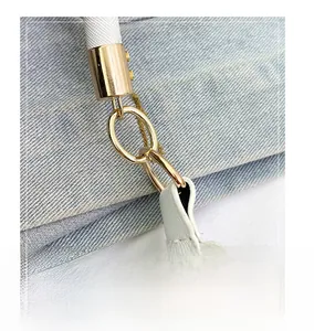 Dettaglio macro degli anelli in metallo dorato su borsa in pelle bianca testurizzata