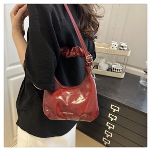 Detail view of dark red glossy shoulder bag with pleated handle and fashion text logo