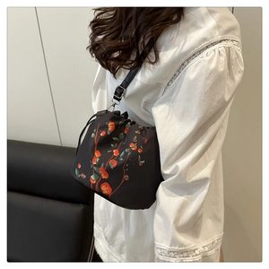 Detail of black drawstring bucket bag with embroidered Ruyi pattern and red fruits