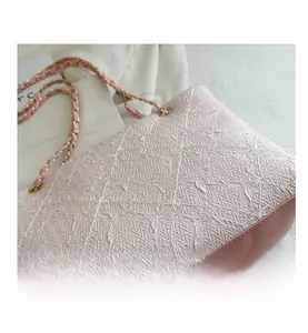 Détail du tissu plissé rose avec broderie croisée blanche et bandoulière en chaîne