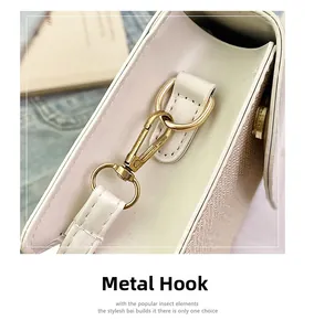 Detail of premium gold-toned metal hook hardware on a cream textured crossbody bag