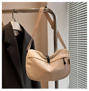 Detail view of cream canvas crescent bag showing woven strap and zipper on hanger