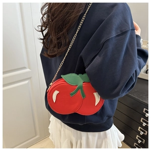 Side view of cherry shaped crossbody bag with red spheres and green leaf detail