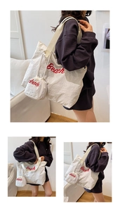 Detail of white canvas tote bag with red Beach embroidery and matching mini drawstring pouch