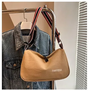 Gros plan du sac en toile kaki avec bandoulière rayée colorée et logo imprimé