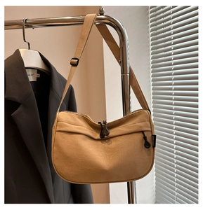 Detail view of khaki canvas crossbody bag featuring adjustable strap and woven side logo