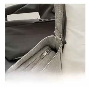 Detail view of smooth metal zipper and silver-grey woven texture on shoulder bag