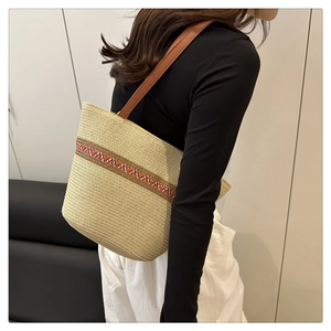 Detailed side view of a large woven straw beach tote with colorful ethnic patterns and straps