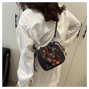 Detail of vintage bucket bag with persimmon print and drawstring closure on model