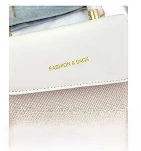 Detail of white leather handbag with gold 'FASHION & BAGS' logo and metallic hardware