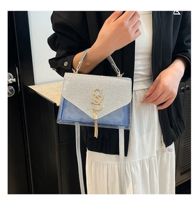 Detail of silver glitter flap and blue transparent bag with gold tassel decoration