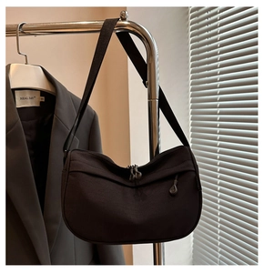 Minimalist black crescent crossbody bag with adjustable nylon strap on metal stand
