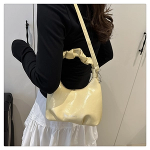 Detail of light yellow patent leather cloud bag with Fashion & Bags logo and pleated handle