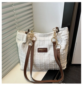 Detail of white tweed tote bag featuring leather logo patch and gold ring chain strap