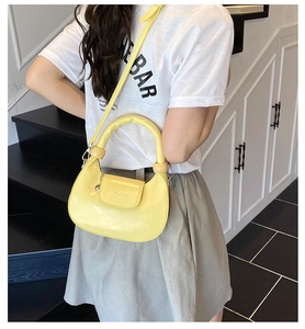 Detailed back view of a yellow crescent bag with thick handle and metal chain pendant