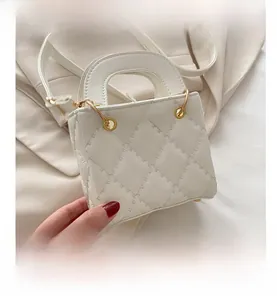 Detail of white quilted square handbag with elegant stitching and golden hardware eyelets