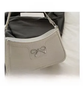 Detail of white crocodile pattern leather handbag with silver metal bow buckle closure