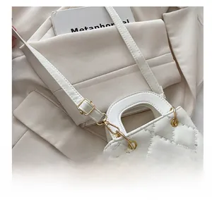 Detail of white quilted handbag showing adjustable gold buckle on faux leather strap