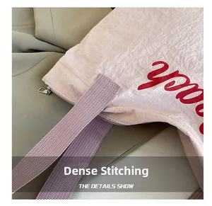 Detail of reinforced stitching and purple woven strap on pink corduroy shoulder bag