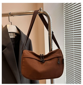 Detail of dark brown nylon crescent crossbody bag hanging on a steel coat rack