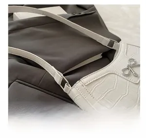 Close-up of white crocodile pattern shoulder bag with a silver metal bow buckle