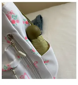 Detail of side pocket on floral shoulder bag with a green umbrella tucked inside