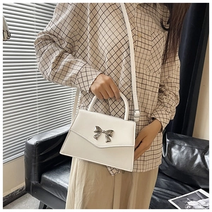 Dettaglio della borsa a patta in pelle PU bianca con fibbia a fiocco in metallo argento