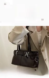 Detail of glossy faux leather shoulder bag with silver buckle strap and biker style design