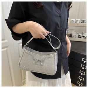 Detail of silver sequin shoulder bag featuring a metallic bow and sleek strap design