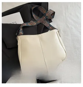 Close-up of cream crossbody bag with a bohemian ethnic pattern wide shoulder strap