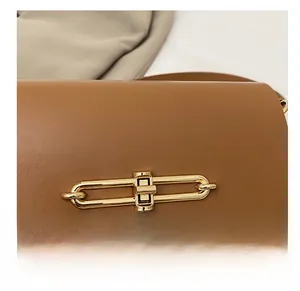 Detailed close-up of a golden metal turn-lock closure on a brown leather handbag