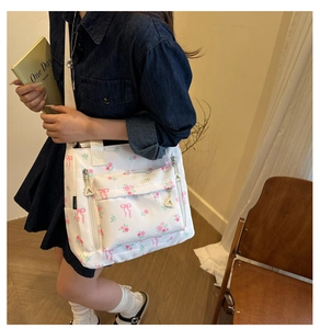 Detail of floral crossbody bag with pink bow patterns and front zipper pockets