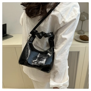 Detail of black patent leather crossbody bag with pleated handle and fashion logo