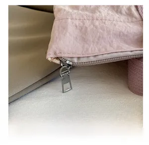 Detailed close-up of a smooth silver metal zipper on a pink fabric shoulder bag