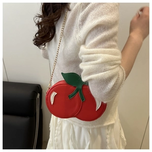 Model wearing a cute 3D cherry shaped crossbody bag with red body and green leaf detail