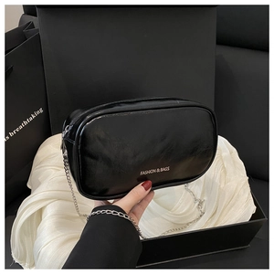 Detail of elegant black chain bag with silver strap and fashion text on luxury gift box