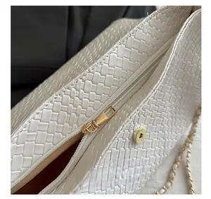 Détail d'un sac tressé blanc avec fermeture éclair dorée et bouton magnétique