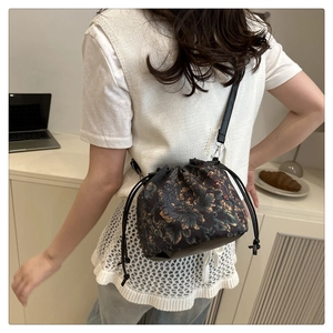 Detail of vintage floral drawstring bucket bag worn by model in a modern lifestyle setting