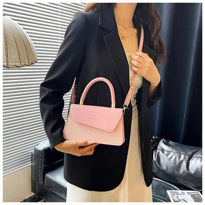 Close-up of pink crossbody bag featuring leather and woven patchwork with gold hardware
