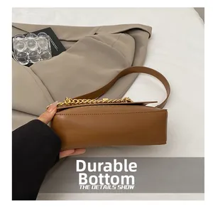 Detail view of the durable bottom and gold chain of this brown leather crossbody bag