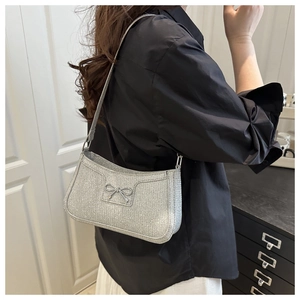 Close-up of a silver glitter shoulder bag featuring a metallic bow detail on black shirt