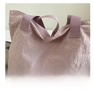 Close-up of pink nylon tote bag featuring red Beach embroidery and wide fabric handles