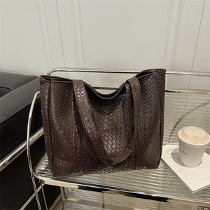 Minimalist dark brown woven tote bag in a stylish office setting with a premium finish