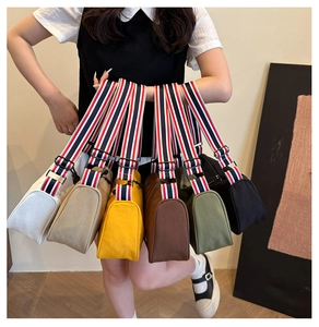 Détail de sacs à bandoulière en toile en six couleurs avec de larges bretelles à rayures