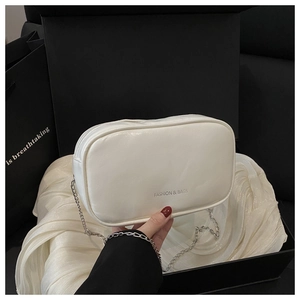 Detail view of cream white chain crossbody bag featuring fashion text and silver metal link