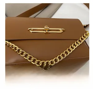 Detail of caramel brown leather crossbody bag with chunky gold chain and metal lock